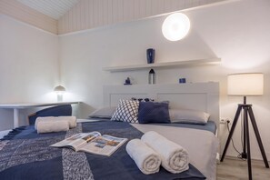 Una habitación de hotel con cama, escritorio, lámpara y mesita de noche.