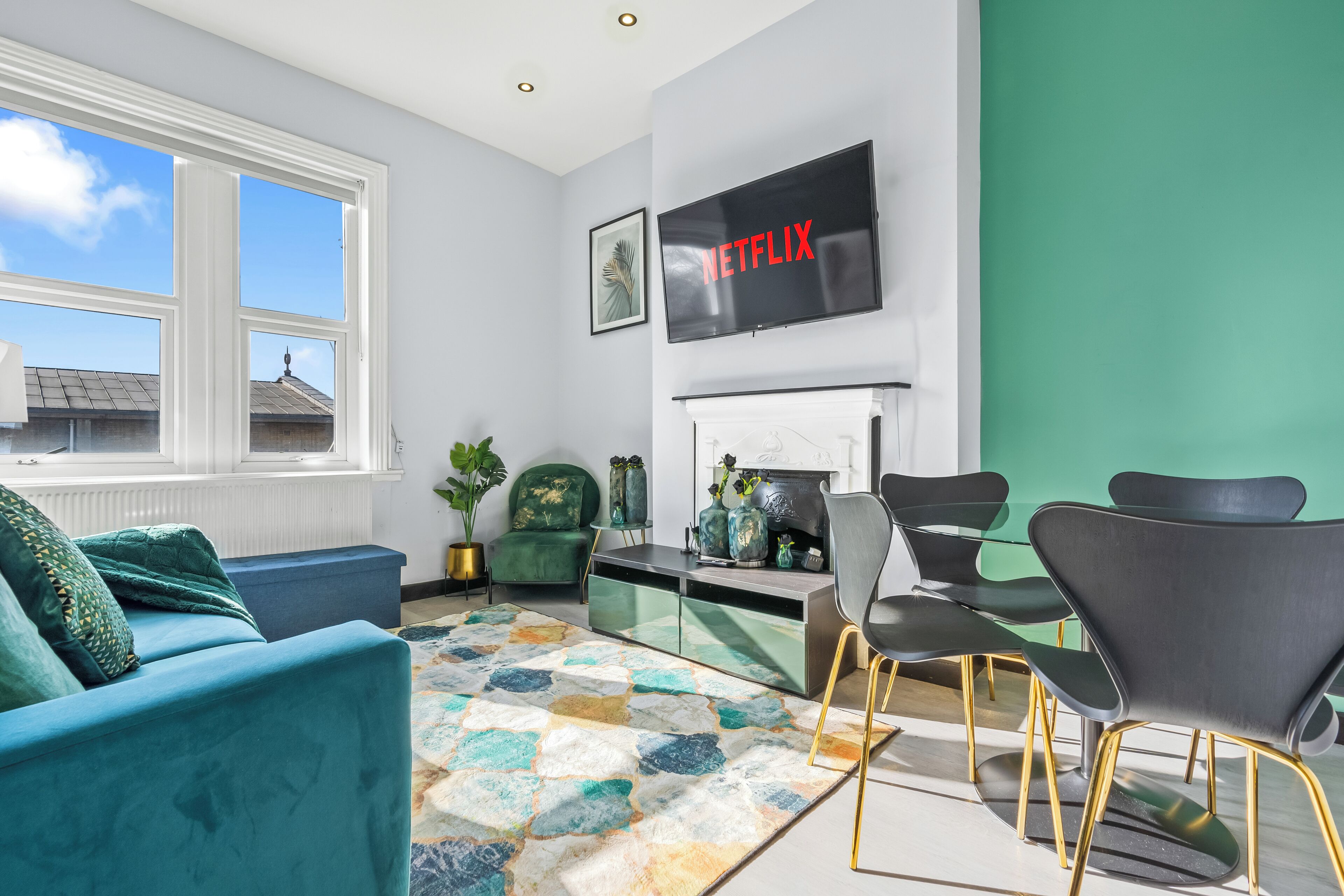Una sala de estar moderna con sofá, sillas, chimenea, televisor y vista al cielo.