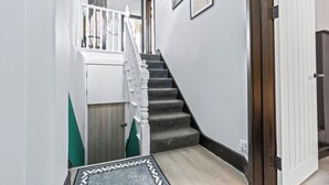 Una escala amb una barana blanca, una porta de fusta i un estenat amb dibuixos a la base.