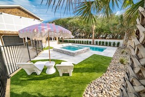 Un jardin avec une piscine, deux chaises longues et un parasol de style tiki.