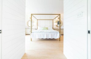 A bedroom with a four-poster bed, bedside lamps, and a white wall. - 6 BR Oceanview, POOL, 2 Min walk to Beach, Game Rm (Kure Beach)