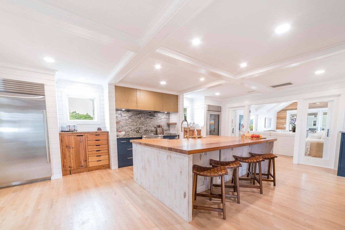 A spacious kitchen with a central island, wooden cabinetry, and a stainless steel refrigerator.