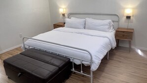A bedroom with a bed, bedside tables, a nightstand, and a black ottoman. - Cozy 1-bedroom completely private guest house in Fresno with refreshing AC (Fresno)