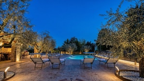 Area piscina con sedie a sdraio, un disegno a forma di bussola sul pavimento e una piscina sullo sfondo.