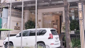 Un edificio con un letrero que dice 'SON TUNG RESIDENCE' y un SUV blanco estacionado en la entrada.