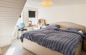 Une chambre à coucher avec un grand lit, un globe terrestre, un manteau de fourrure et une lampe.
