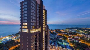 A high-rise building with multiple floors, large windows, and a view of the cityscape and water. - The Panora Pattaya by PH (Pattaya)