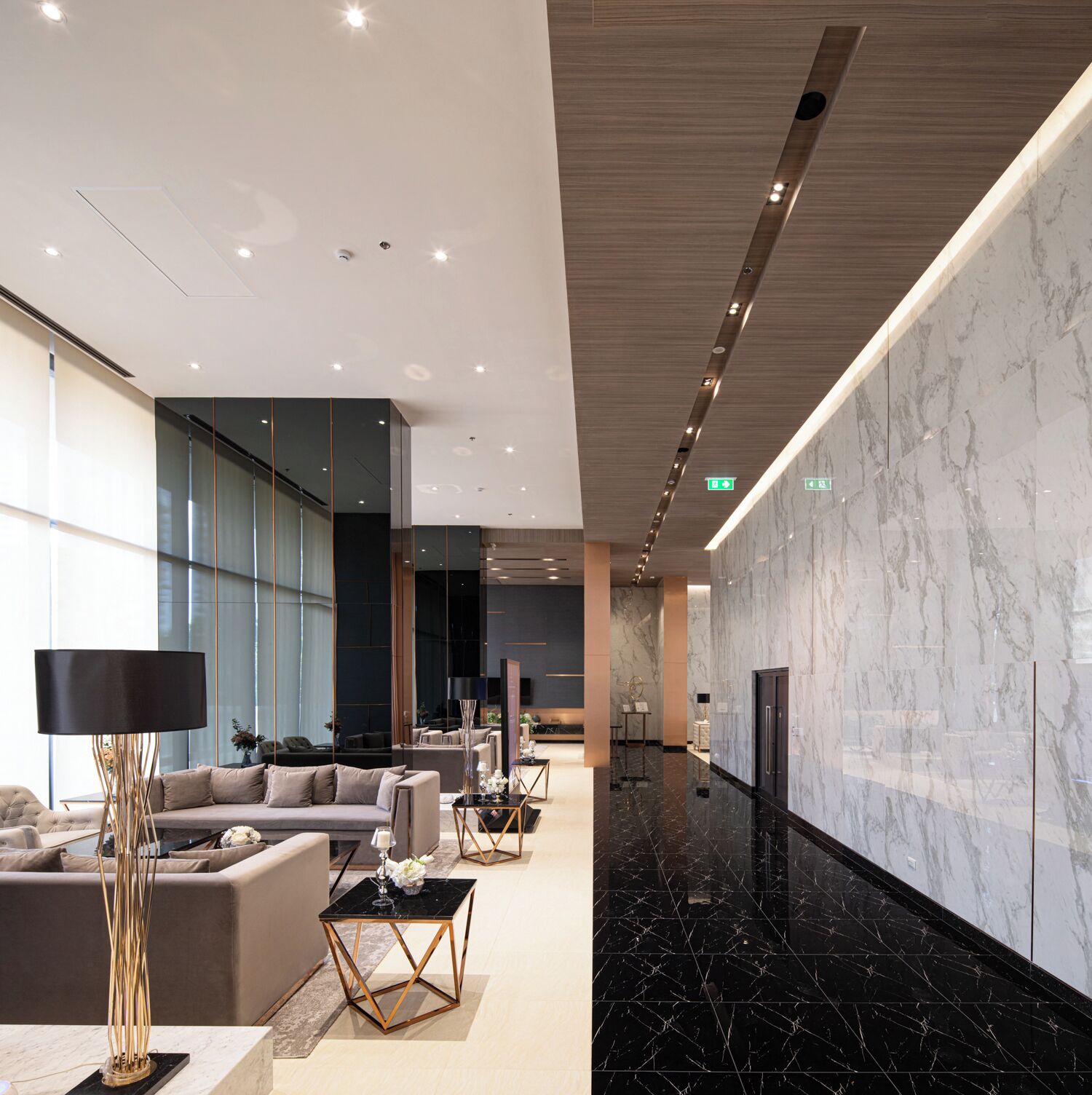 A modern lobby with a marble wall, sofas, a coffee table, and a floor lamp.