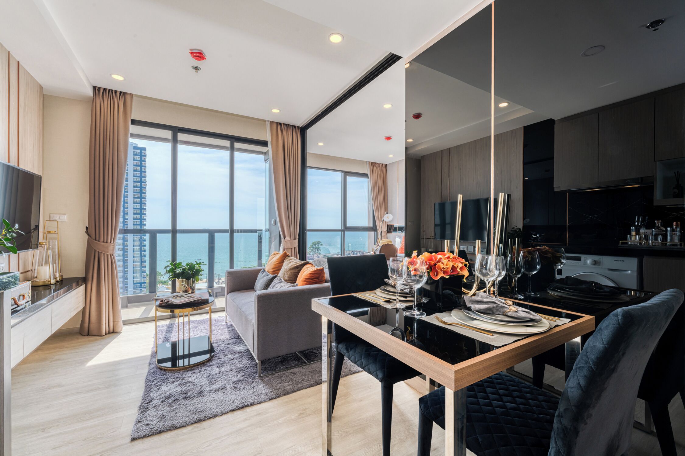 A modern living room with a sofa, a dining table set for two, and a view of the city through large windows.