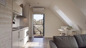 Eine moderne Küche mit Einbauofen, ein Essbereich mit weißem Tisch und Stühlen sowie ein Blick durch eine Glastür.