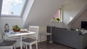 Ein Loft-Wohnraum mit Essbereich, einem grauen Sofa, einem Fernseher und einem kleinen Tisch mit Lampe.