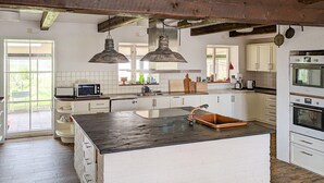 Una cocina con armarios blancos, una isla central, un microondas y una estufa.