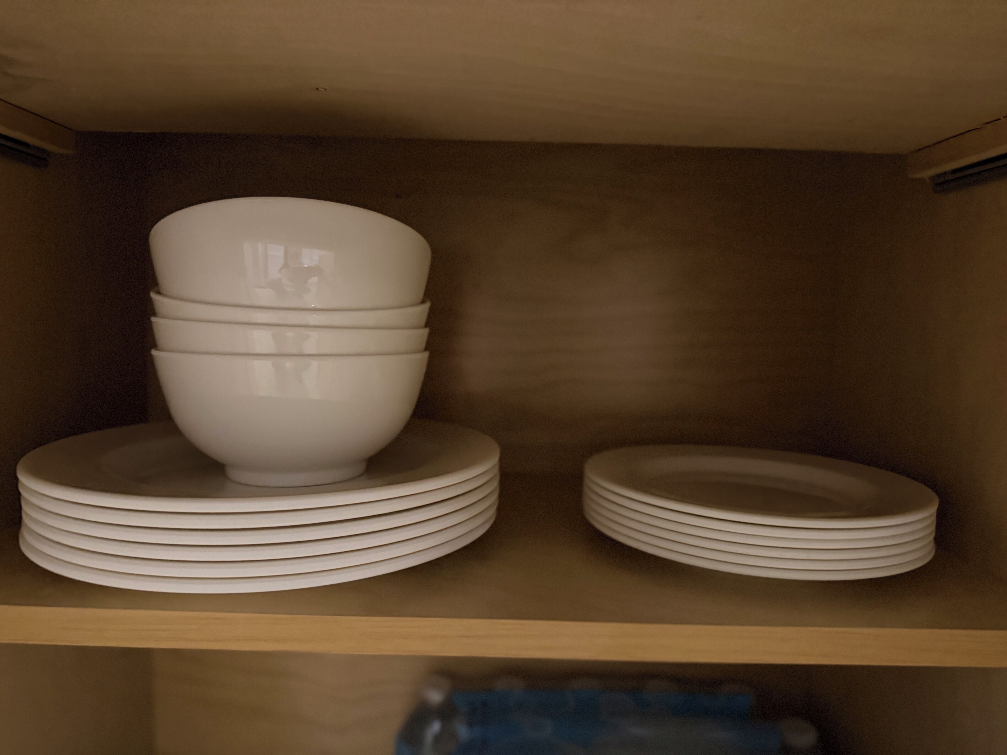 A shelf with stacked white bowls and plates.