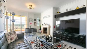 Un salon moderne avec un canapé en cuir, une table basse en verre, un téléviseur et une cheminée.