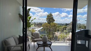 A modern balcony with a sofa, chairs, a round table, and a potted plant. - Modern coastal stay in the heart of Scarborough (Scarborough)