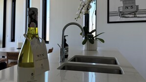 A modern kitchen with a wine bottle, a sink, a ceiling fan, and a framed picture on the wall. - Modern coastal stay in the heart of Scarborough (Scarborough)