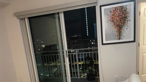 A living room with a white sofa, a colorful rug, a glass door leading to a balcony, and a framed artwork on the wall. - Luxury Prime Brickell Condo, Pool, Gym, Free Parking (Miami)