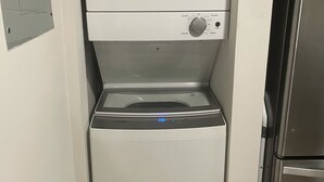 A compact washer and dryer unit with a control panel, located in a small kitchen area with a refrigerator. - Luxury Prime Brickell Condo, Pool, Gym, Free Parking (Miami)