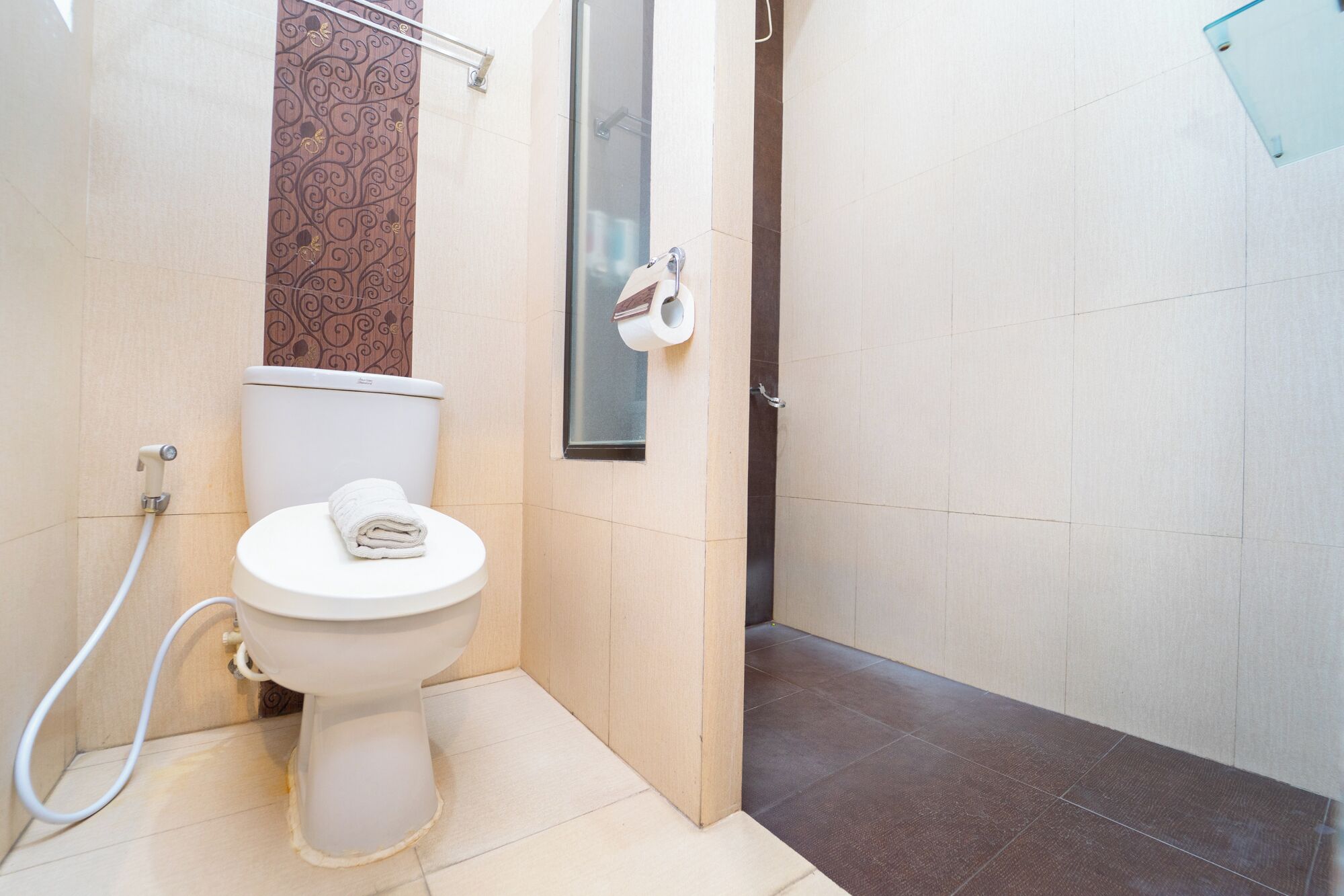 A bathroom with a toilet, a towel, a shower, and a glass door.