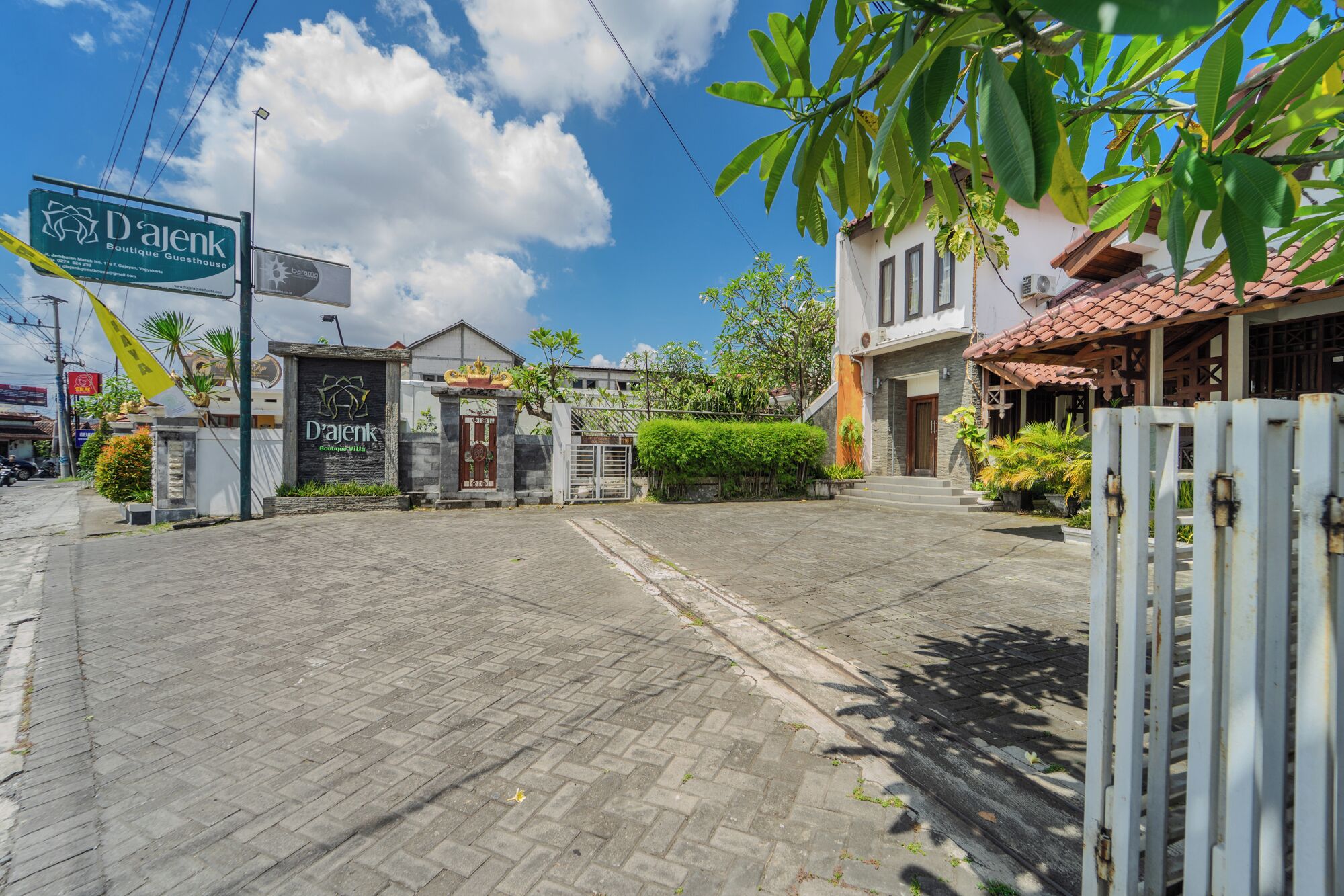 A boutique guesthouse with a paved entrance, a signboard, and a gated entrance.