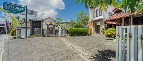 A boutique guesthouse with a paved entrance, a signboard, and a gated entrance.