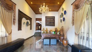 Un vestíbulo con una araña, decoraciones murales ornamentales, un mostrador de recepción y una escalera.