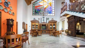 Una habitación amplia con un gran ventanal de vitrales, muebles de madera y una escalera.