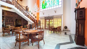 Un vestíbulo espacioso con una imponente escalera, muebles de madera y un amplio ventanal de vitral.
