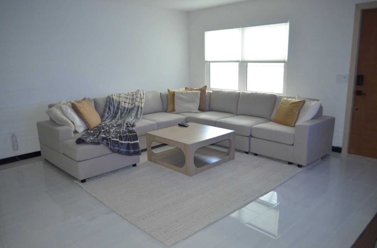 Una sala de estar moderna con un sofá modular, una mesa de centro y un gran ventanal que proporciona luz natural.