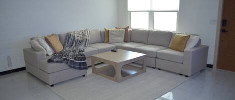 Una sala de estar moderna con un sofá modular, una mesa de centro y un gran ventanal que proporciona luz natural.