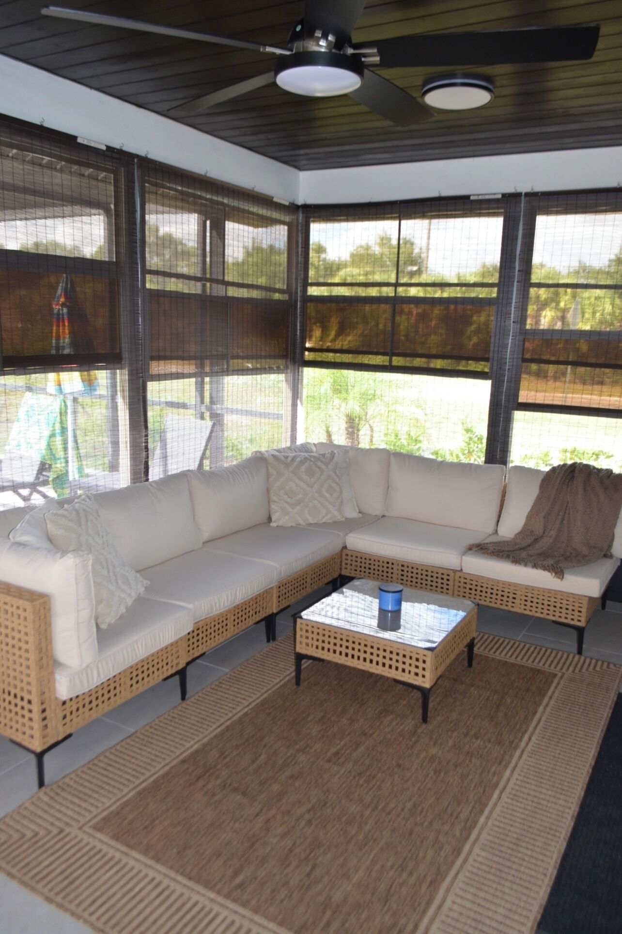 Un espacio al aire libre cubierto con un sofá modular, una mesa de centro y un ventilador de techo.