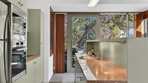 A modern kitchen with a built-in oven, a stainless steel refrigerator, and a granite countertop. - Squatters Run 8: central ski-view stay w/ parking (Thredbo)