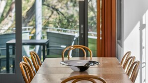 A dining table with chairs, a glass bowl, and a view of outdoor seating. - Squatters Run 8: central ski-view stay w/ parking (Thredbo)