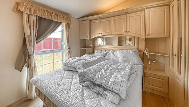 Een slaapkamer met een bed, gordijnen en houten kasten.