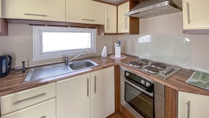 Eine kleine Küche mit Spüle, Herd, Backofen und Holzschränken.