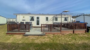 Ein Wohnmobil mit einer Terrasse, Sitzgelegenheiten im Freien und einer überdachten Veranda.