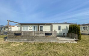 A mobile home with a deck, a grill, and a small garden area.