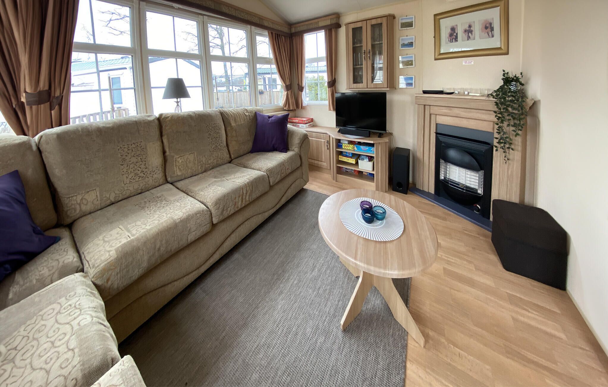 Una sala de estar con sofá, televisión, chimenea y una mesita con objetos decorativos.
