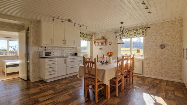 Een keuken met houten kastjes, een eettafel met stoelen en uitzicht op het landschap.