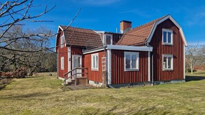 Een rode houten woning met een schuin dak, schoorsteen en klein portaal.