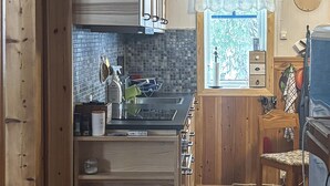 Une cuisine de taille réduite avec un mur recouvert de carreaux, une fenêtre offrant une belle vue et une horloge au mur.