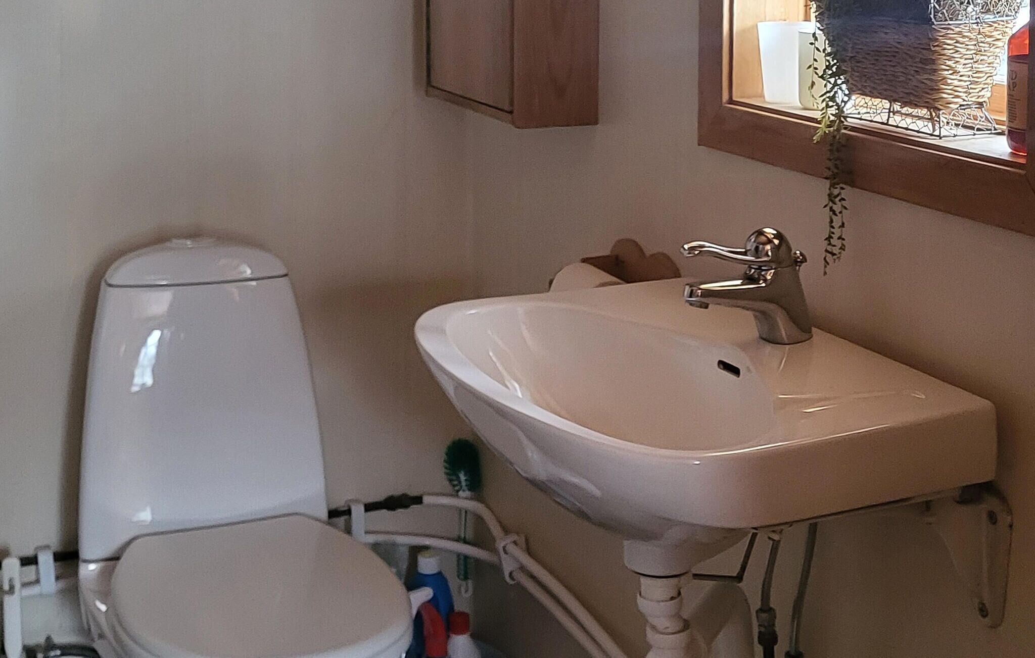 Een badkamer met toilet, wastafel en raam.