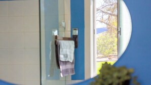 A bathroom with a mirror, a towel rack, and a window with a view of trees. - Perfect 3-bed Higgins Surf Shack@the park by the Point in enchanting Middleton (Middleton)