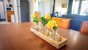 A wooden tray with four glass vases containing yellow roses on a wooden table. - Perfect 3-bed Higgins Surf Shack@the park by the Point in enchanting Middleton (Middleton)