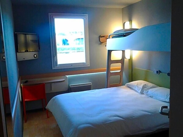 A bunk bed room with a desk and chair, a window, and a wall-mounted TV.