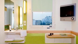 Un bagno con lavandino, specchio, finestra e televisore a parete.