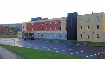 Ein mehrgeschossiges Gebäude mit Parkplatz davor.