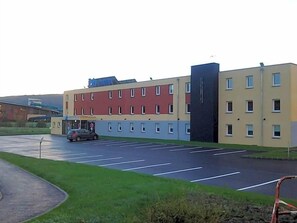 A multi-story building with a parking lot in front.