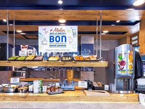 A breakfast buffet with various food items and a coffee machine. - Ibis Budget Givet (Givet)