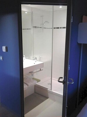 Une salle de bain moderne avec une douche à parois de verre, un lavabo blanc et un porte-serviettes.